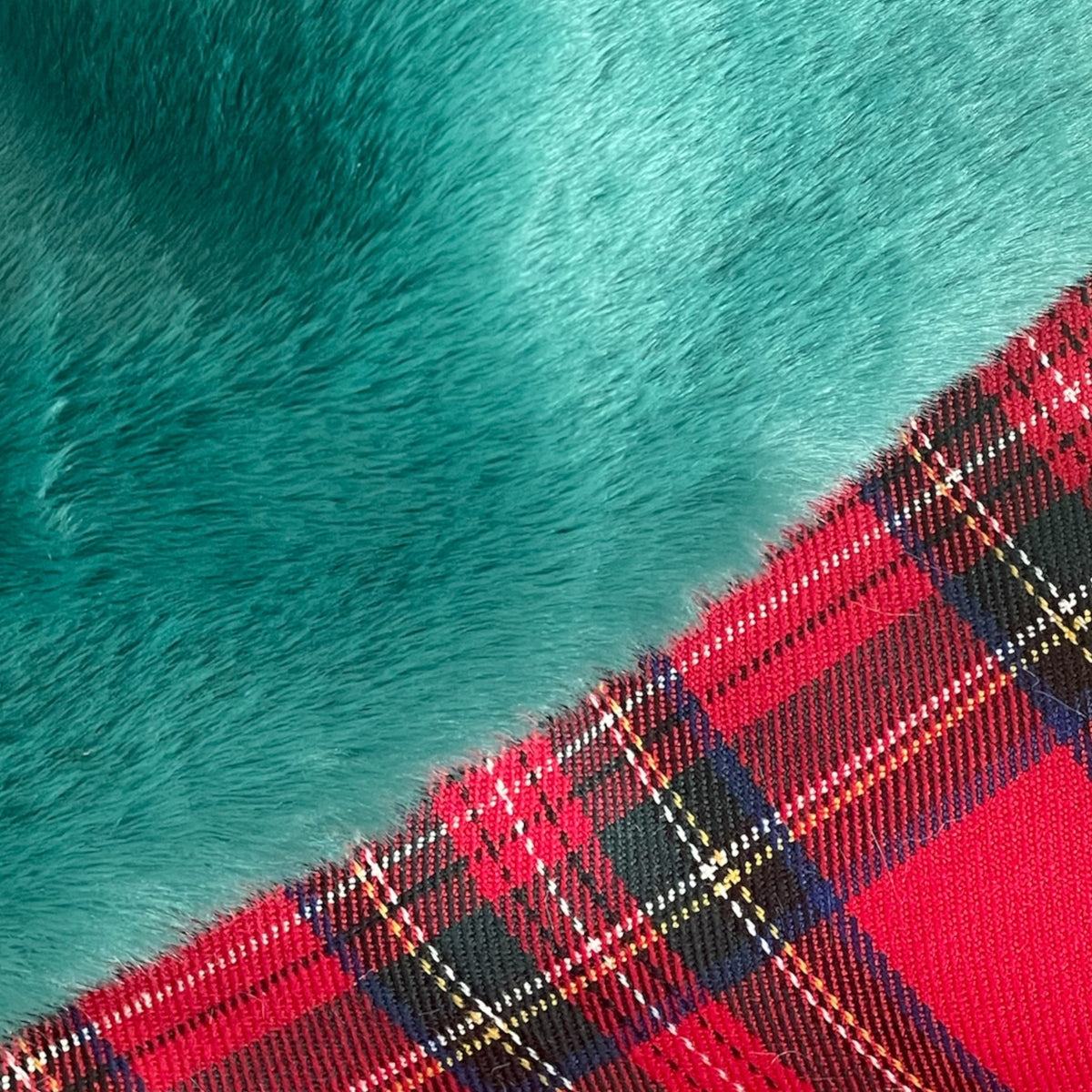 Primo piano della calza natalizia tartan con risvolto verde in pelliccia sintetica e targhetta in legno personalizzata con nome inciso.