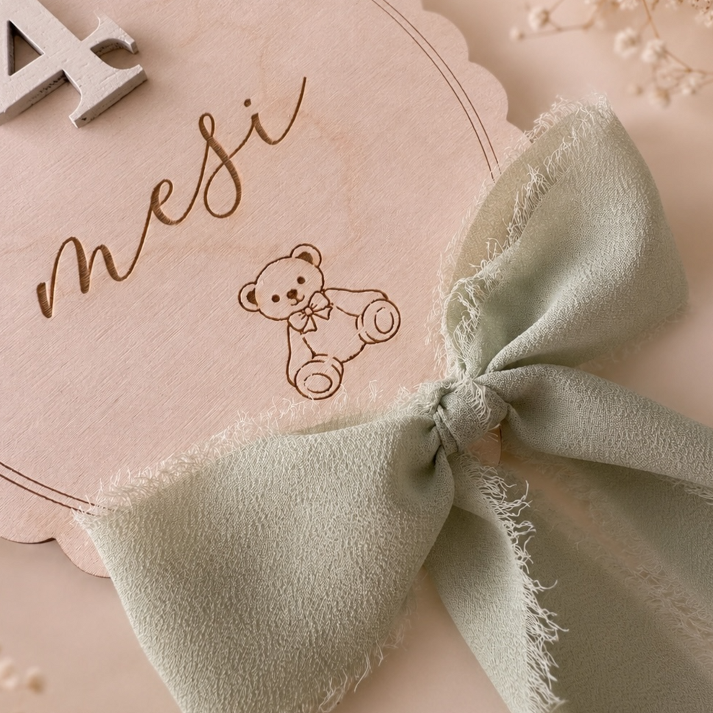 Dettaglio delle Milestone Cards Teddy con orsetto inciso, scritta mese e fiocco verde salvia sfrangiato