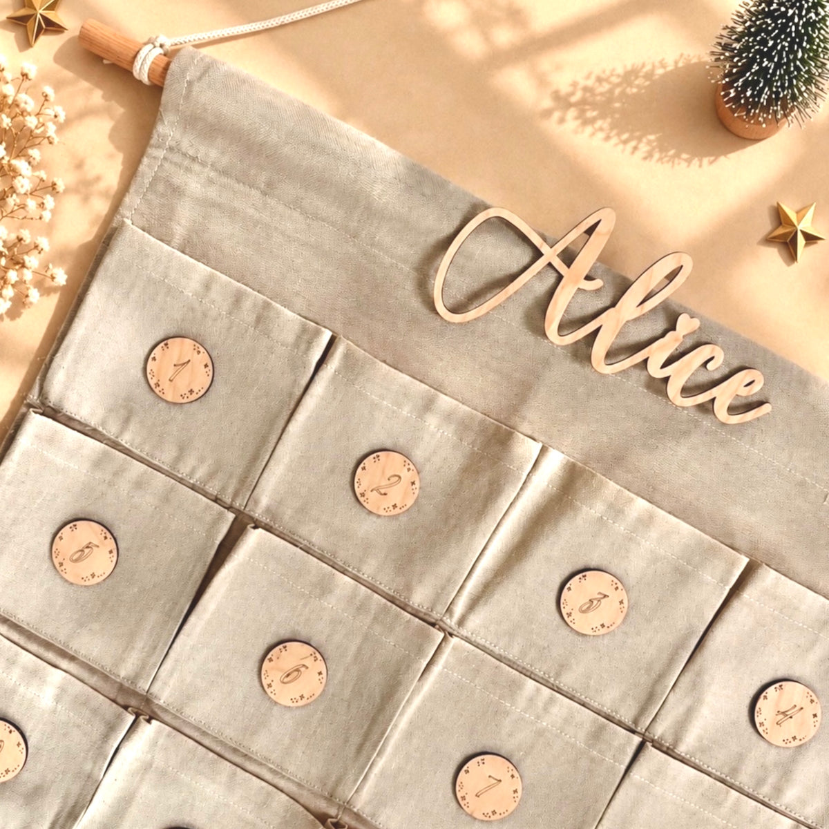 Dettaglio del nome personalizzato in legno del calendario dell'avvento in tessuto con 24 tasche