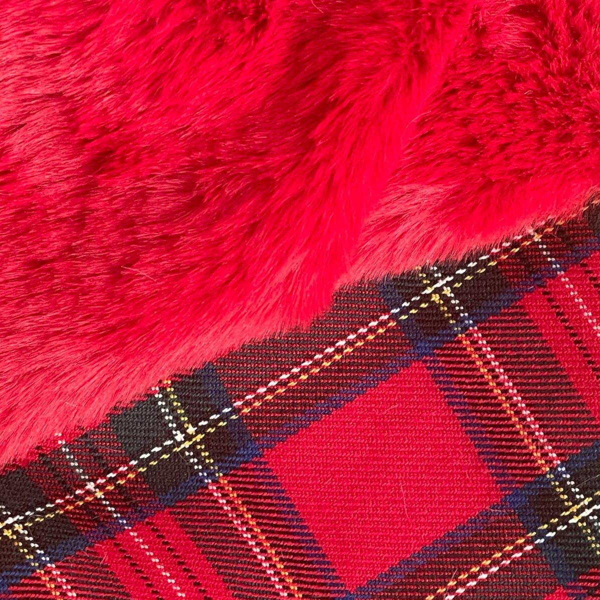 Dettaglio della calza natalizia tartan con morbido risvolto rosso, cordoncino dorato e targhetta personalizzata in legno naturale.