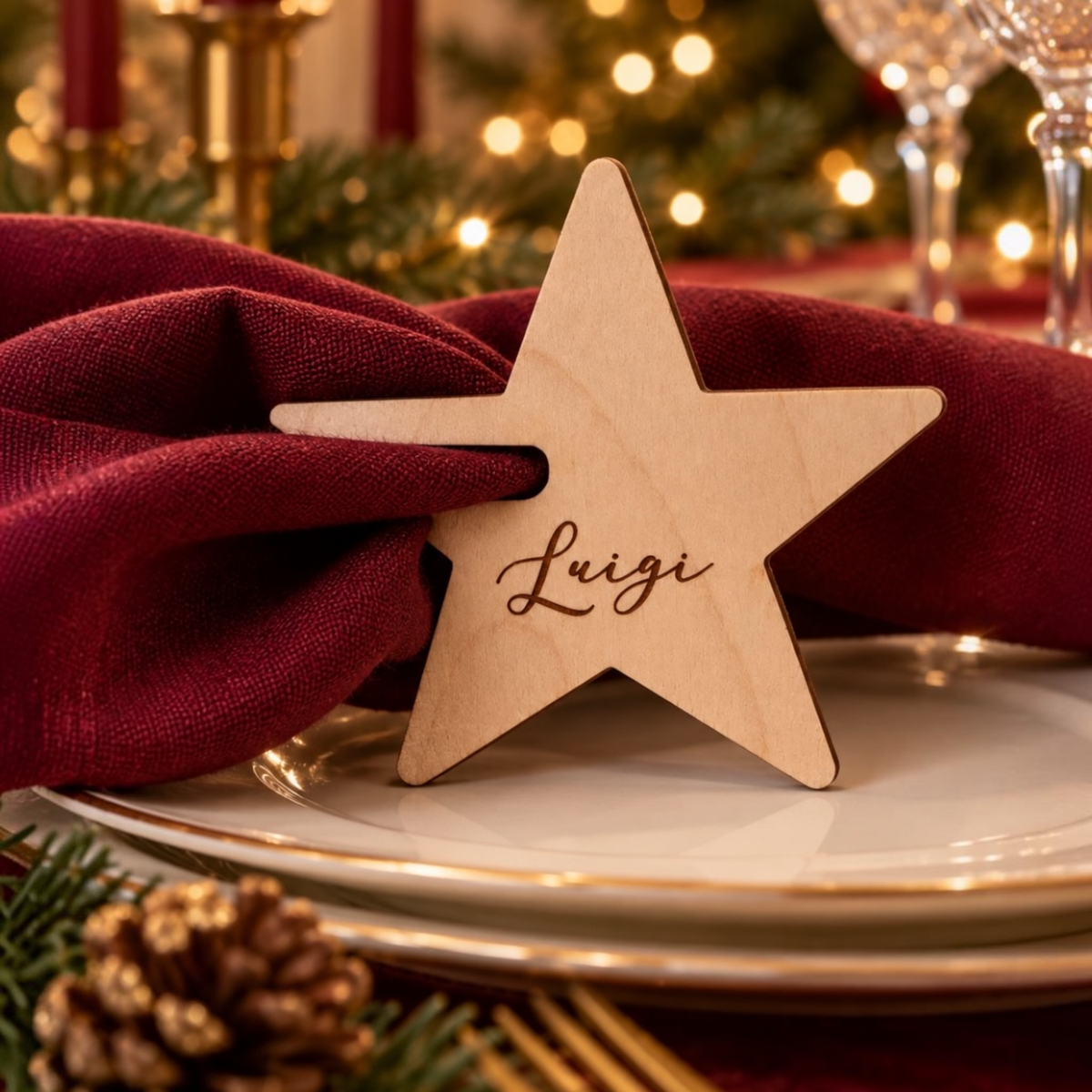 Segnaposti natalizi fermatovagliolo personalizzati in legno di betulla, a forma di  stella, con nomi incisi su tovaglioli bordeaux. 
