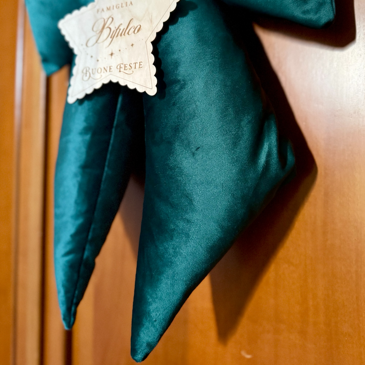 Primo piano del velluto verde del fiocco natalizio imbottito, con tessuto morbido, pieghe decorative e finitura elegante.