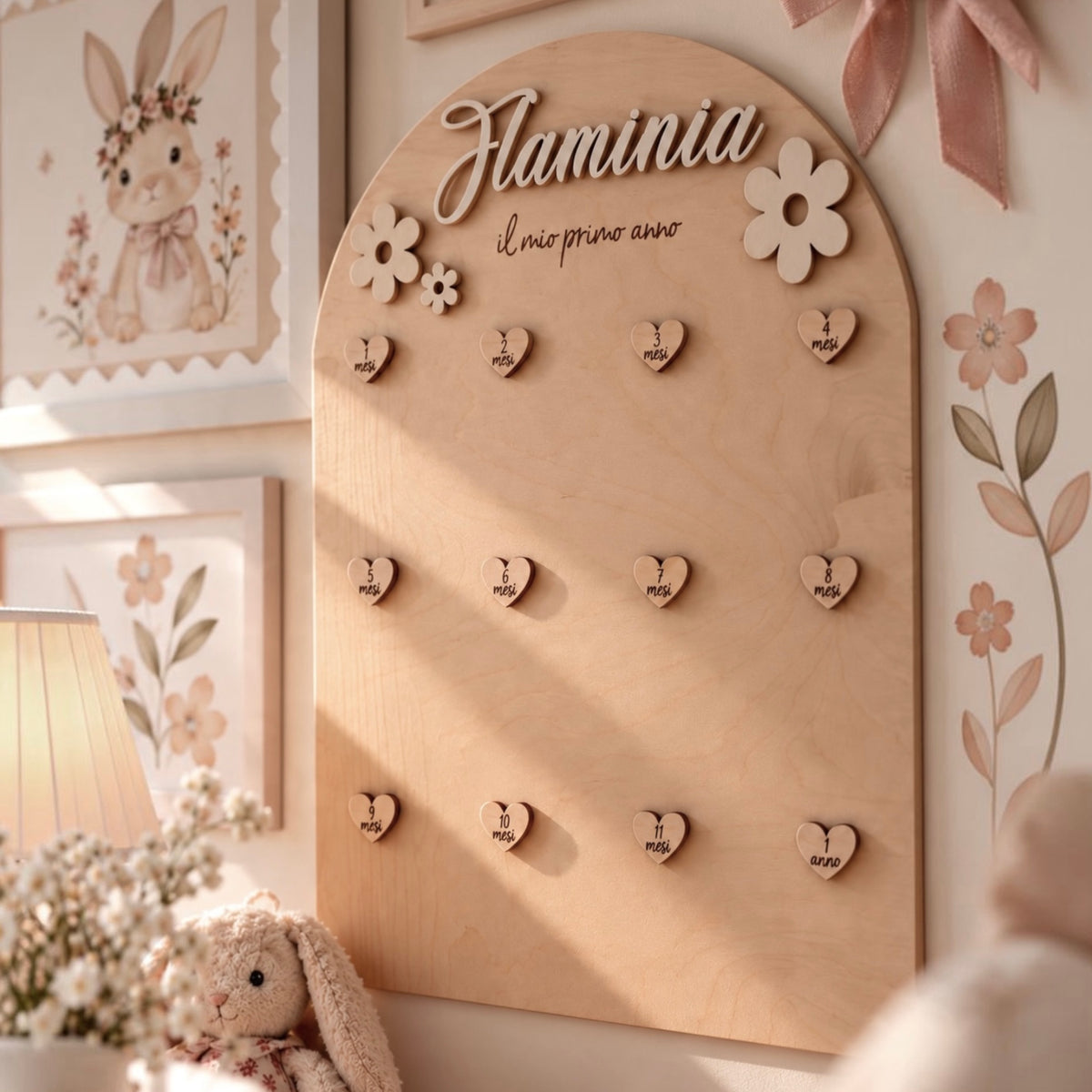 Vista frontale del portafoto primo anno Flower in legno con nome Flaminia in rilievo, tre fiori decorativi e dodici cuoricini magnetici numerati.