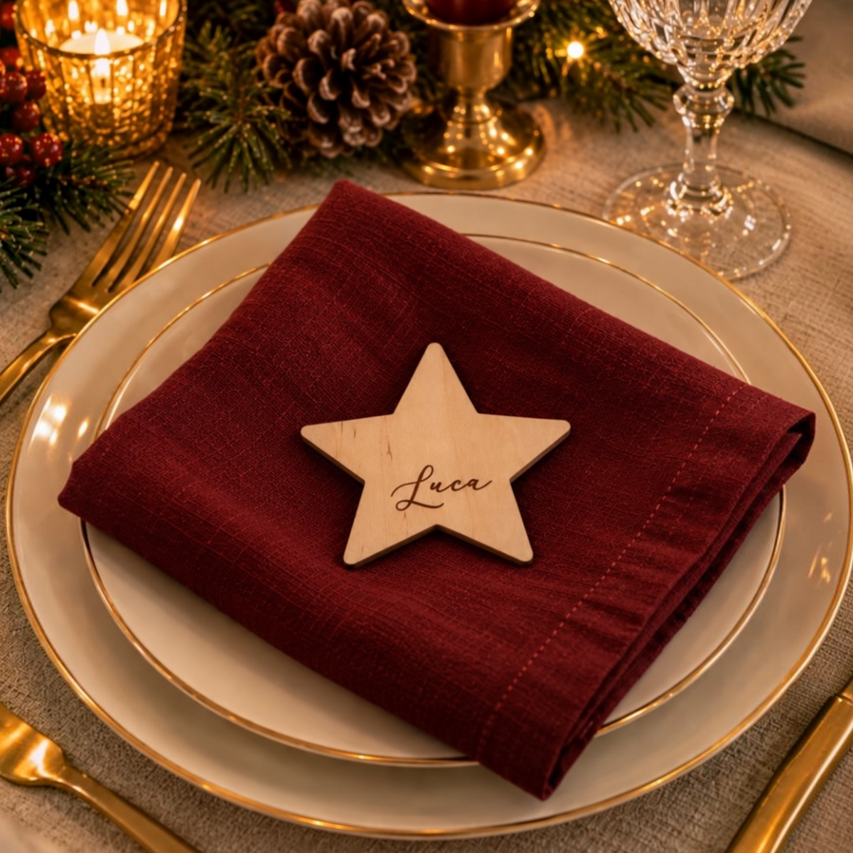 Segnaposto natalizio a forma di stella in legno di betulla, personalizzato con nome inciso e posizionato su un tovagliolo bordeaux per la tavola di Natale.